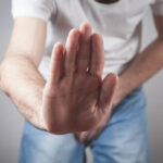 Caucasian man with hand holding his crotch and showing stop gesture