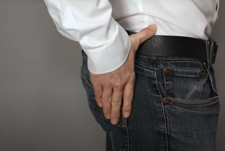 Man in jeans with one hand on his glutes